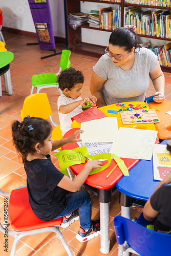 A teacher helps her preschool students with an art project about recycling