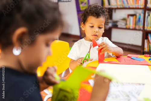Fotografie Latino children in a kindergarten cut out colored paper in a creative and fun ac