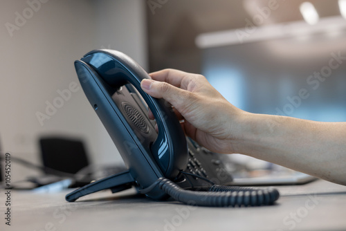 close up man hand touching telephone for call  or connecting with partner,vendor or customer at computer desktop operation room, hotline and helpline concept photo