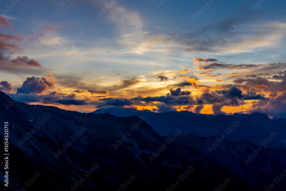 Sunset burning red and orange sky above the snow summits and rocky peaks of the Alps. Beautiful mountain sunset and sunrise in Chamonix valley on the ascent to Montblanc Sunset burning red and orange sky above the snow summits and rocky peaks of the Alps. Beautiful mountain sunset and sunrise in Chamonix valley on the ascent to Montblanc