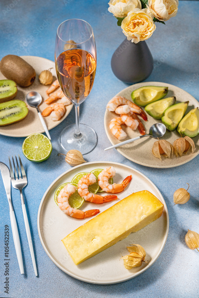 Romantic dinner setting featuring cheese, shrimp, kiwi, avocado, and rose wine Romantic dinner setting featuring cheese, shrimp, kiwi, avocado, and rose wine