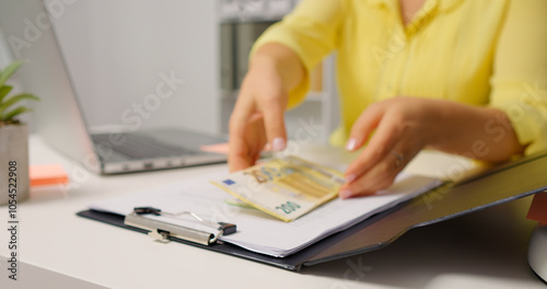 Woman opening the clipboard and raising a pile of money. Accountant taking money out of a clipboard.