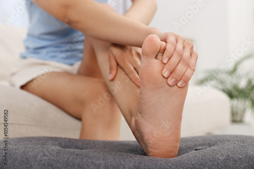 Woman suffering from foot pain at home, closeup