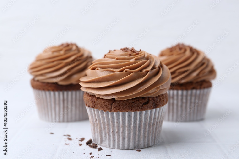 Tasty cupcakes with chocolate cream on white tiled table, closeup Tasty cupcakes with chocolate cream on white tiled table, closeup