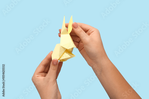 Female hands with beige rabbit on blue background photo