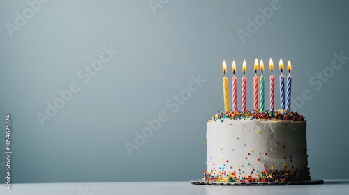 Birthday cake with colorful candles and sprinkles on a subtle background.