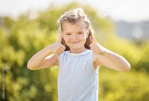 Happy girl, portrait and park with thumbs up for holiday, weekend or winning in nature. Young, female person or child and kid with smile, like emoji or yes sign for great, amazing or good review photo