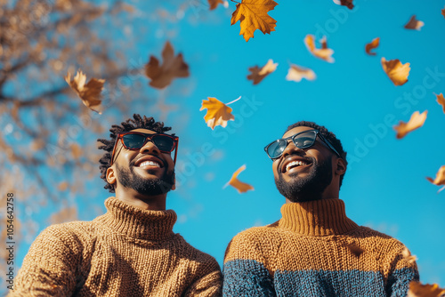 African American men couple Sunny weather hipster people Romantic walk, happy couple with warm pullovers in autumn park. Smiling friends hugging in golden leaves. smiling in falling autumn leaves. photo