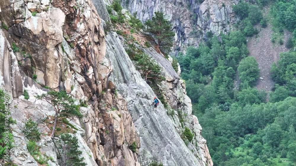 Climber ascending steep rock face with safety rope Climber ascending steep rock face with safety rope