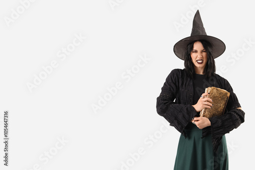 Beautiful young scary woman dressed as witch for Halloween with spell book isolated on white background
