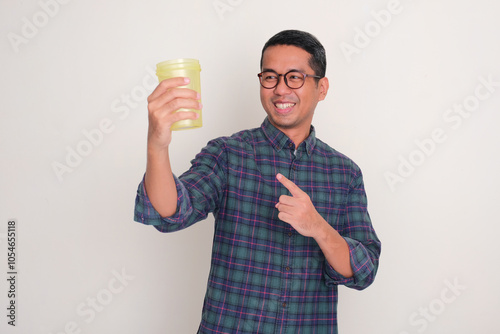 A man smiling happy when staring and pointing at drinking tumbler that he hold photo