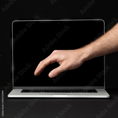 A hand reaching towards a laptop screen against a dark background.