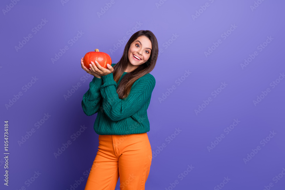 Photo of pretty young girl hold pumpkin empty space wear pullover isolated on purple color background Photo of pretty young girl hold pumpkin empty space wear pullover isolated on purple color background