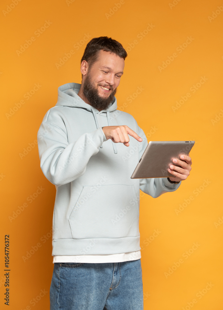 modern bearded man using tablet surprised approves recommends on orange background isolated modern bearded man using tablet surprised approves recommends on orange background isolated
