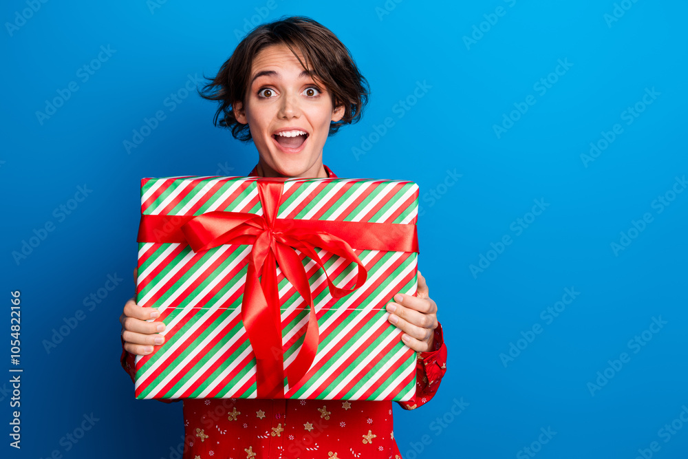 Portrait of nice young girl hold present empty space wear red xmas new year shirt isolated on blue color background Portrait of nice young girl hold present empty space wear red xmas new year shirt isolated on blue color background