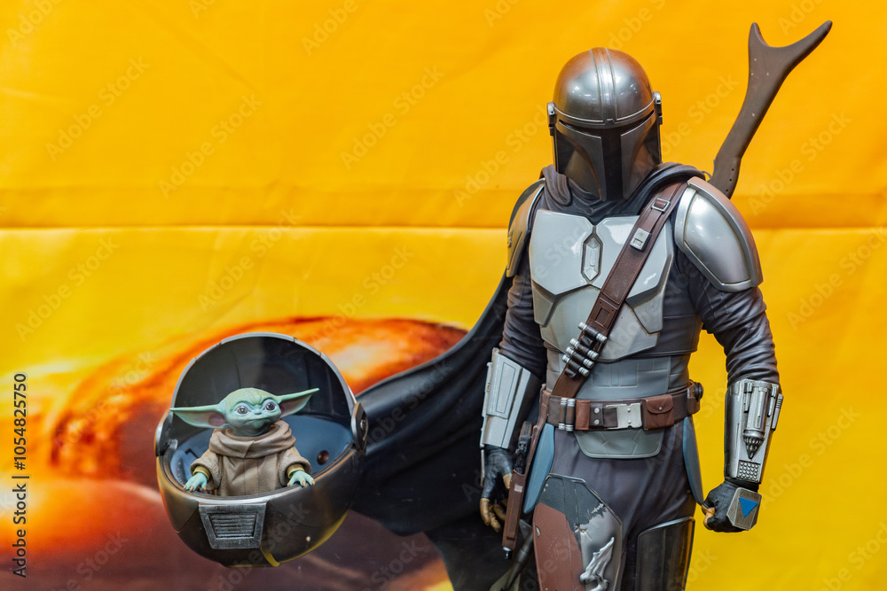 Naklejka premium 8th Comic Con Convention In GUAYAQUIL, ECUADOR - AUG 06, 2023 -Mandalorian and Grogu figurines against vibrant orange background, inspired by the Star Wars series. Perfect for sci-fi and collectible