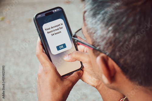 A South Asian man got his social media account restricted for 24 hours message on the mobile phone. Selective focus.