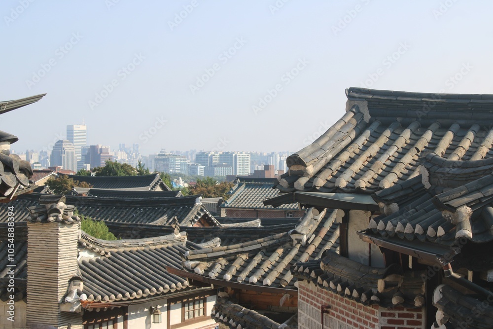 Traditional Korean hanok style rooftops with urban skyline in the background