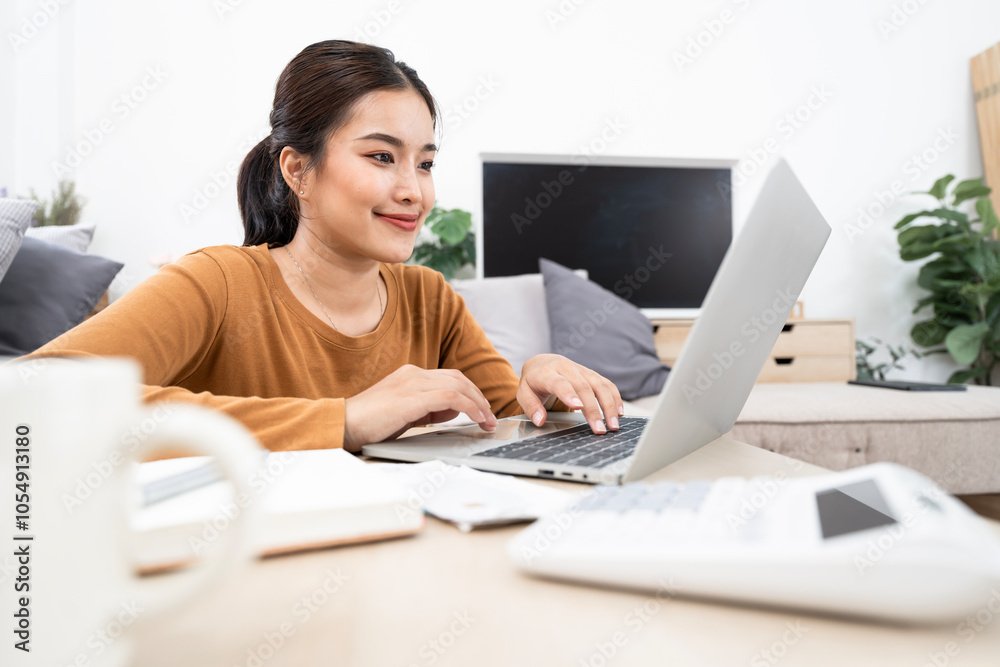 Beautiful young Asian woman working with laptop computer in living room at home Beautiful young Asian woman working with laptop computer in living room at home