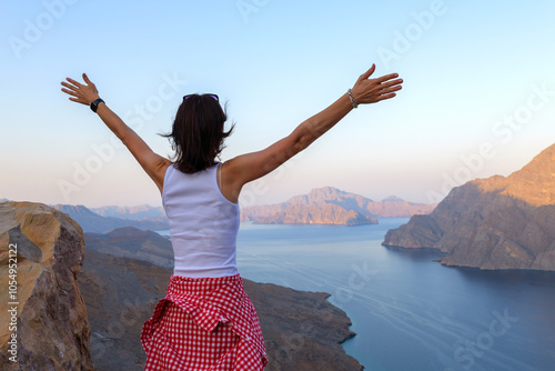 woman admires the panoramic view of the Musandam fjords from a rocky cliff at sunset, Khor Najd, Oman photo