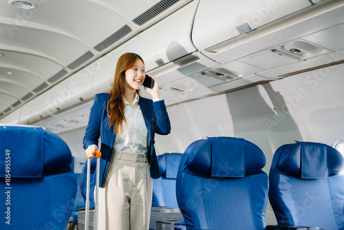 Asian female passenger of airplane sitting in comfortable seat while working laptop and tablet. Travel in style,