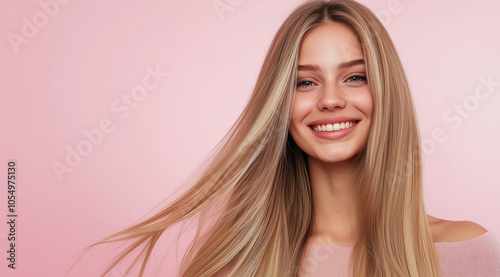 Radiant blonde woman with glossy, honey-blonde hair and a warm smile, standing against a light pink background to showcase her straight, flowing hairstyle