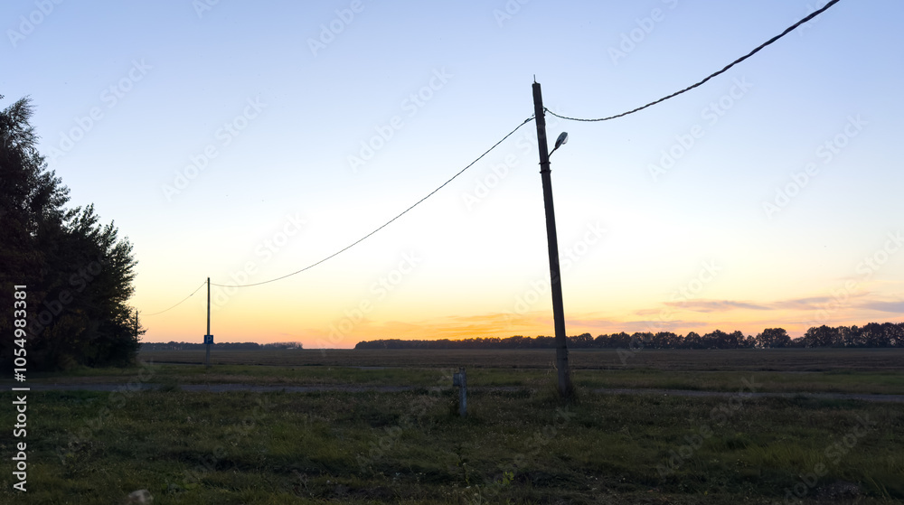 A field with two power lines and a pole in the middle