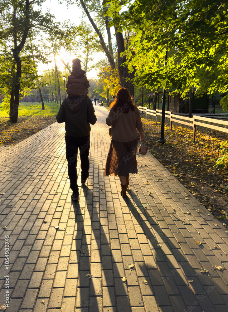 A man and woman are walking down a brick path with a child on the man's back A man and woman are walking down a brick path with a child on the man's back