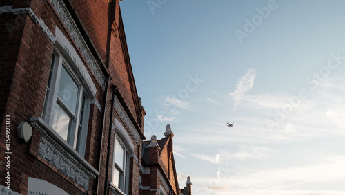 Canvas Print Airplane flying over typical english terraced houses in london suburb at sunset