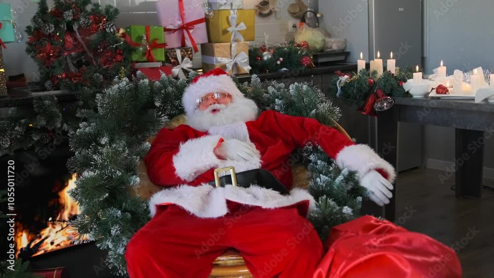 Tired Santa resting in a chair by the fireplace among fir branches lit candles stroking his belly on Christmas Eve. Tired Santa resting in a chair by the fireplace among fir branches lit candles stroking his belly on Christmas Eve.