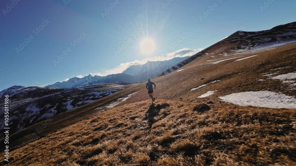 Aerial view of a man in sportswear running fast across fields. A guy exercising outdoors in nature in the mountains covered with snow. View from below near the legs, healthy lifestyle Aerial view of a man in sportswear running fast across fields. A guy exercising outdoors in nature in the mountains covered with snow. View from below near the legs, healthy lifestyle