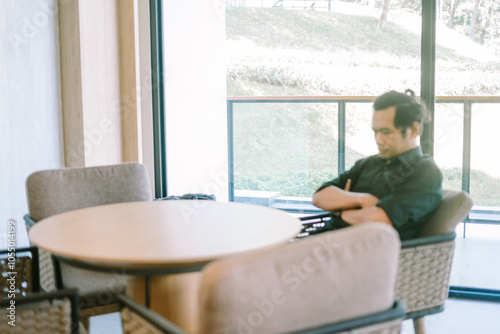 Man sitting in a hotel lobby, relaxed and contemplative, surrounded by modern decor