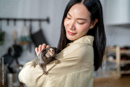 Photography Asian young woman owner play with Marmoset monkey in kitchen at home