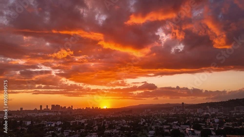 Dramatic orange clouds in beautiful fiery sunset sky over Los Angeles cityscape and West Hollywood / Century City skyline. Aerial hyperlapse timelapse view.
