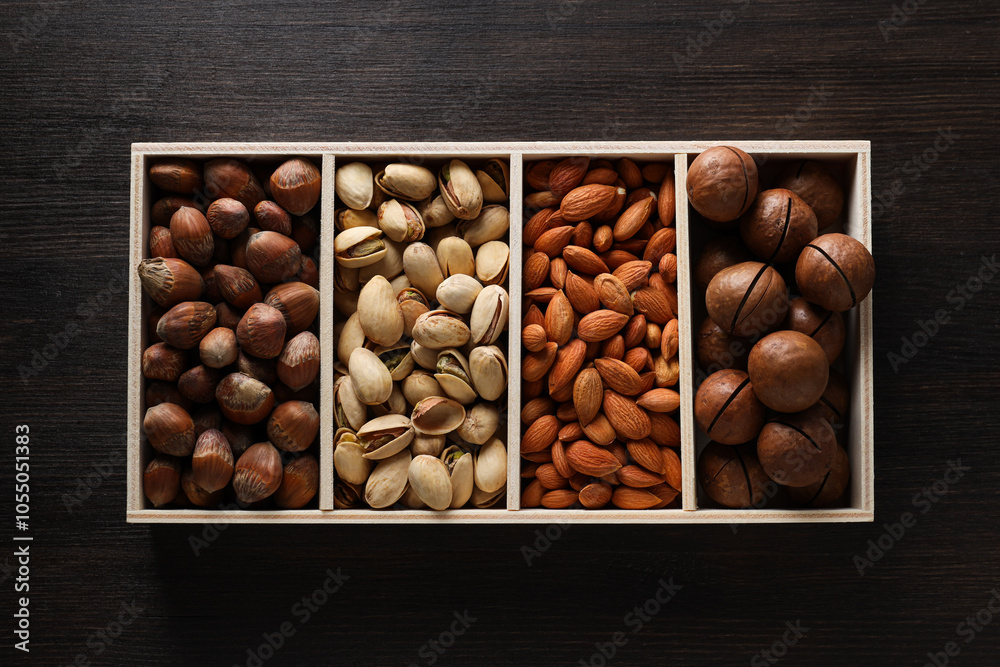 Fototapeta premium Wooden box with different nuts on a dark background