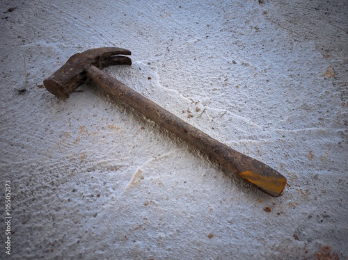 The picture shows a hammer. It looks old and used, with a worn wooden handle and a rusty metal head.
 photo