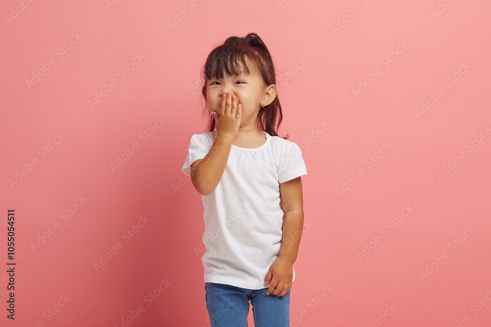 Little Asian girl covers her mouth with happiness, does not expect a pleasant surprise from her parents, being grateful and pleasantly shocked, isolated on a pink background Little Asian girl covers her mouth with happiness, does not expect a pleasant surprise from her parents, being grateful and pleasantly shocked, isolated on a pink background