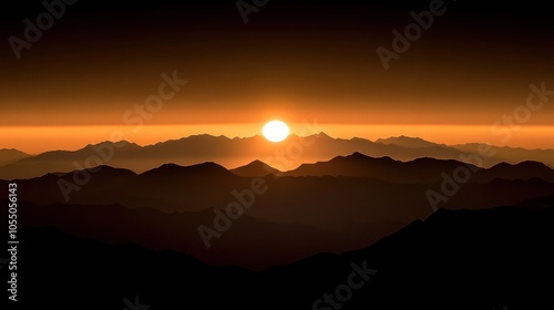 A vibrant sunrise over a range of mountains. The sun is just breaking the horizon, casting an orange glow over the landscape.