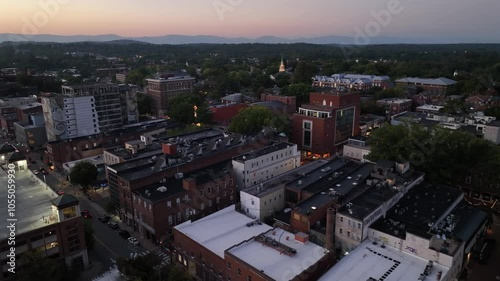 Housing area and residential area of downtown during sunset time. Aerial flyover american town at dusk. Historic buildings in city center. Apartment blocks and driving cars on main street. photo