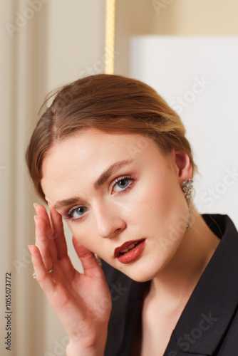 A woman in a white shirt and a necklace. She has a beautiful ring on her hand.