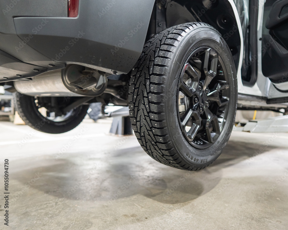 Car on a lift during tire change. Car on a lift during tire change.