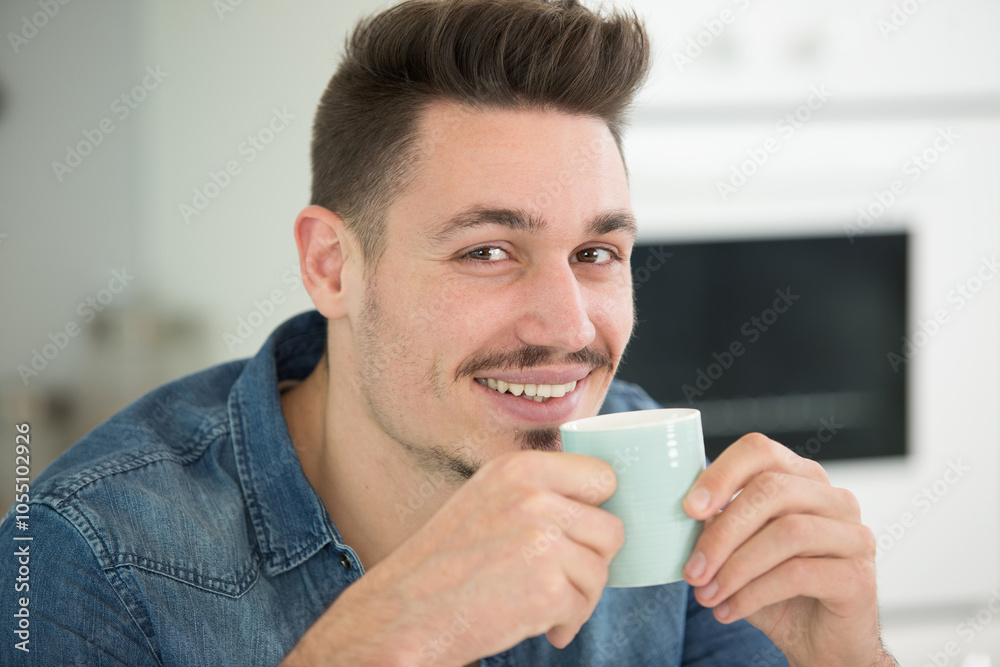 handsome man drinking coffee at home in the kitchen