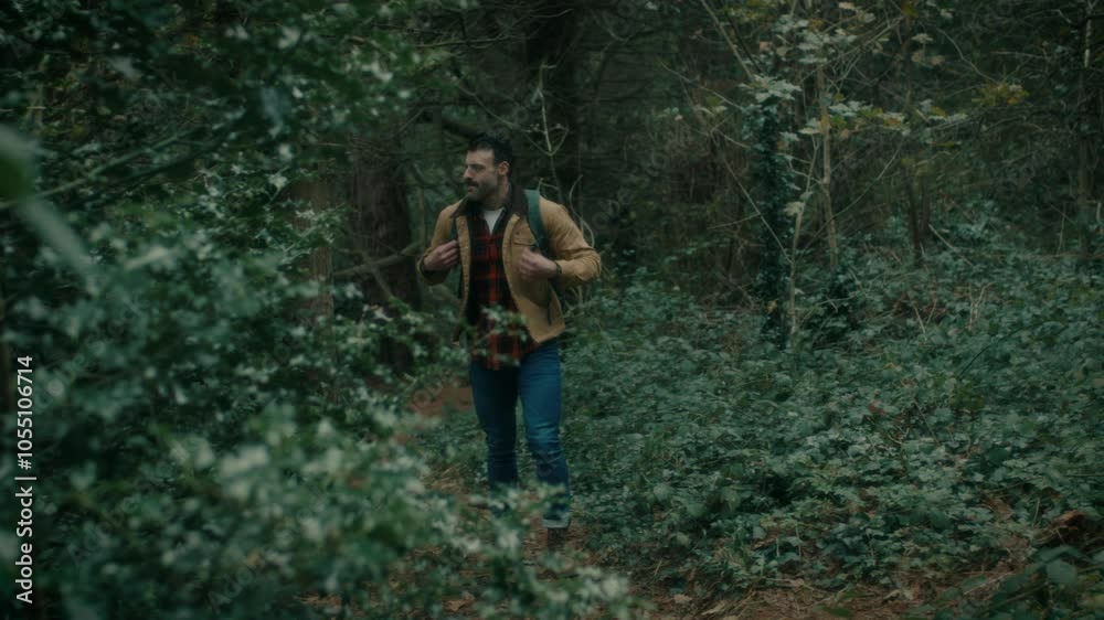Man hiking, walking in the natural forest, looking around, nature. Trekking with a backpack walks through the forest. Man hiking, walking in the natural forest, looking around, nature. Trekking with a backpack walks through the forest.