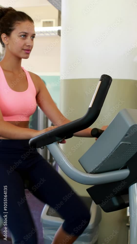 Vertical Video of fit brunette working out on the exercise bike at the gym Vertical Video of fit brunette working out on the exercise bike at the gym