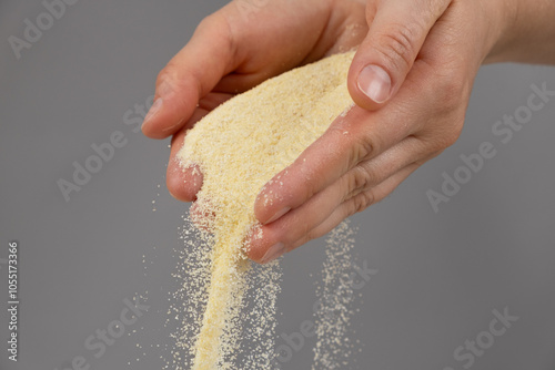 Tableau sur toile Hands pouring dry semolina durum flour uncooked organic semolina close-up gray b