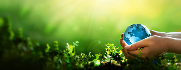 Earth Day.Hand holding crystal earth globe. Environment day, save clean planet, ecology concept.Renewable energy-based green businesses can limit climate change and global warming.	