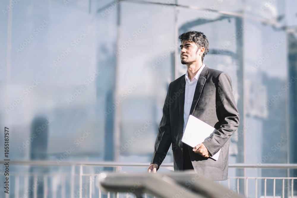 Walking young businessman commuting outside walking to work during his morning commute in the city. Walking young businessman commuting outside walking to work during his morning commute in the city.