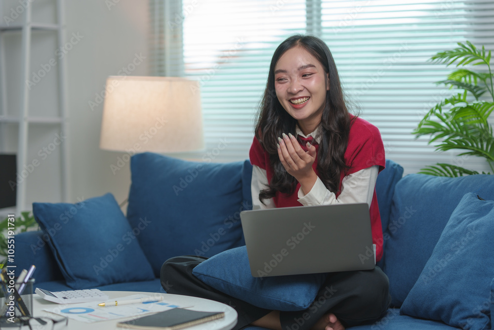 Naklejka premium Businesswoman, cheerful young Asian woman sitting with laptop on sofa in home office Online learning, chatting, video calling, online business contacts working concept learning at home.
