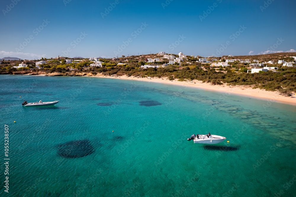A serene beach on Paros Island, Greece, with golden sands, clear turquoise waters, and gentle waves. Framed by rocky cliffs and lush greenery, it's an idyllic Mediterranean escape under the sun.