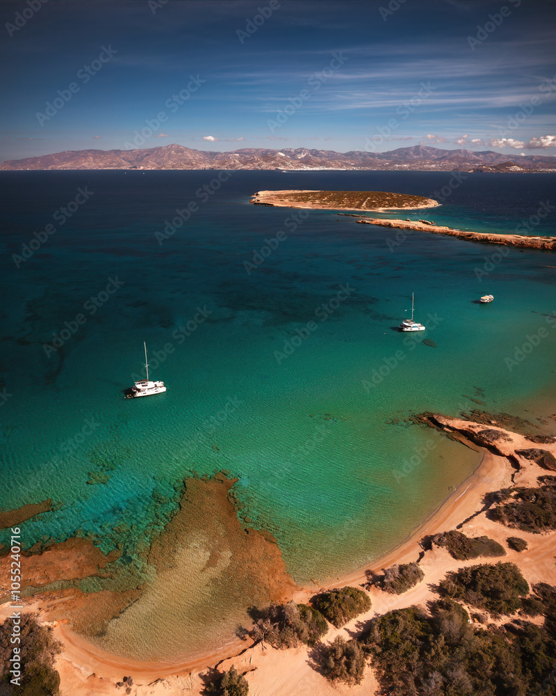 A serene beach on Paros Island, Greece, with golden sands, clear turquoise waters, and gentle waves. Framed by rocky cliffs and lush greenery, it's an idyllic Mediterranean escape under the sun.